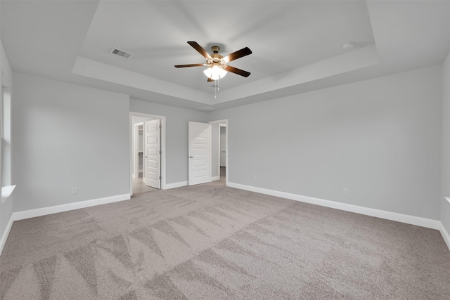 unfurnished bedroom with a tray ceiling, ceiling fan, and light colored carpet