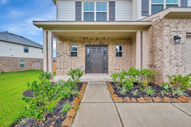 view of exterior entry featuring covered porch and a lawn