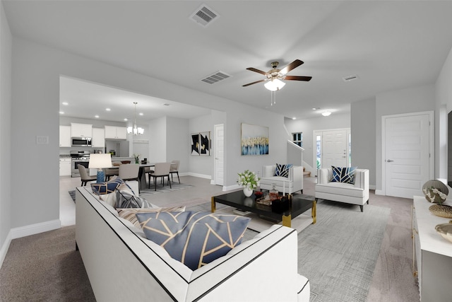 living room with carpet and ceiling fan with notable chandelier