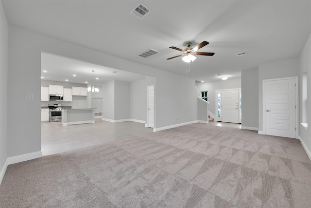 unfurnished living room with light carpet and ceiling fan with notable chandelier