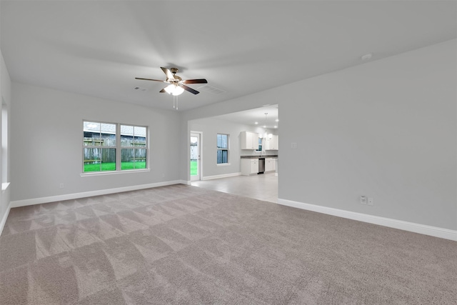 unfurnished living room featuring light colored carpet and ceiling fan with notable chandelier