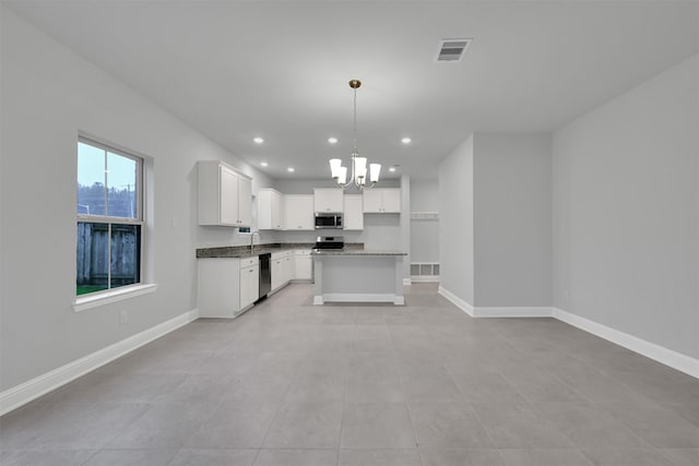 kitchen with a center island, an inviting chandelier, pendant lighting, white cabinets, and appliances with stainless steel finishes