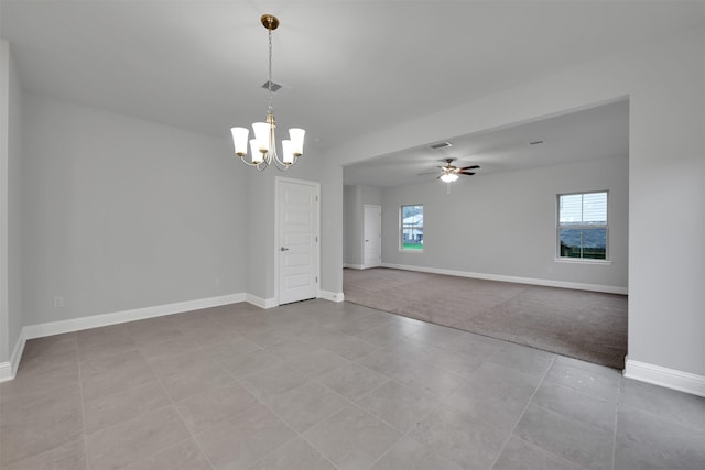 tiled spare room featuring plenty of natural light and ceiling fan with notable chandelier