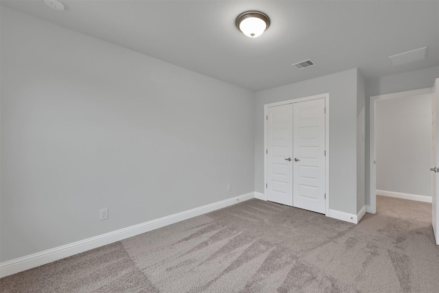 unfurnished bedroom featuring light colored carpet and a closet