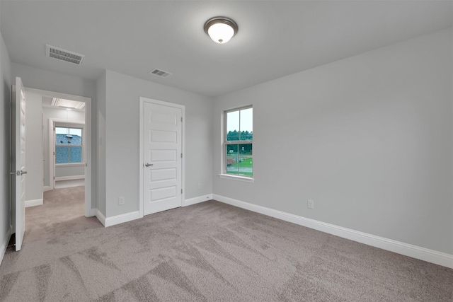 unfurnished bedroom with a closet and light colored carpet