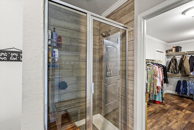 bathroom with hardwood / wood-style floors, a shower with shower door, and ornamental molding