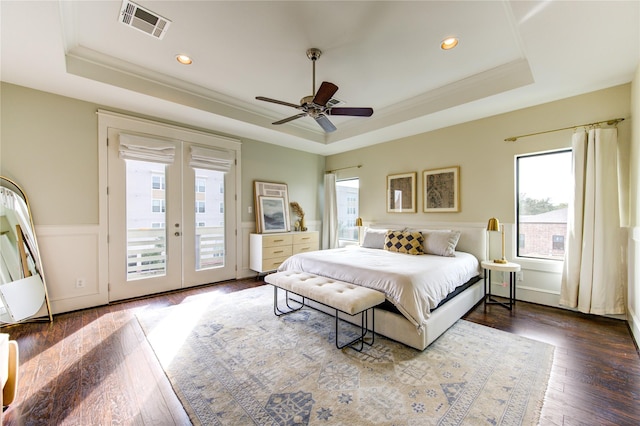 bedroom with ceiling fan, hardwood / wood-style floors, a tray ceiling, and access to outside