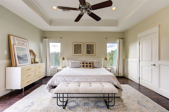 bedroom featuring ceiling fan, dark wood-type flooring, multiple windows, and a tray ceiling