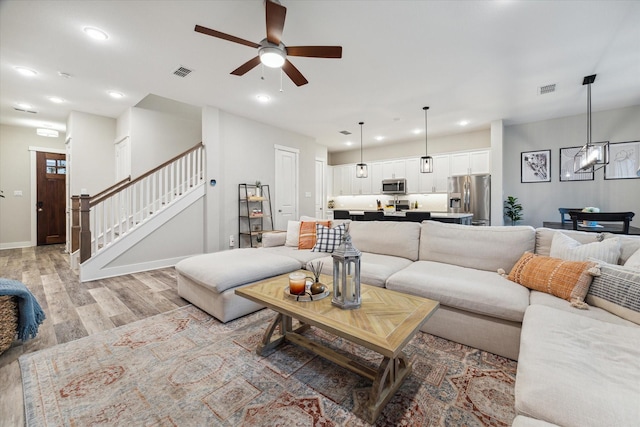 living room with ceiling fan and light hardwood / wood-style flooring