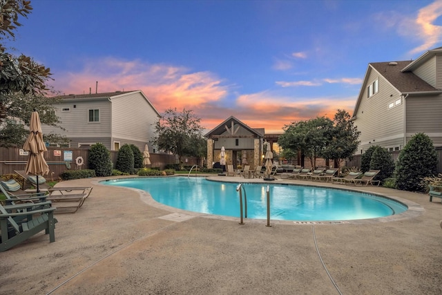 pool at dusk with a patio area