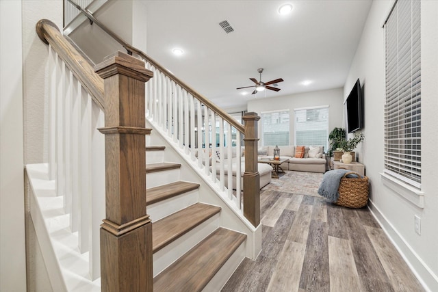 stairway with ceiling fan and wood-type flooring