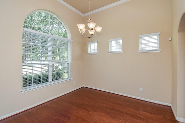 unfurnished room with hardwood / wood-style flooring, a wealth of natural light, crown molding, and a notable chandelier