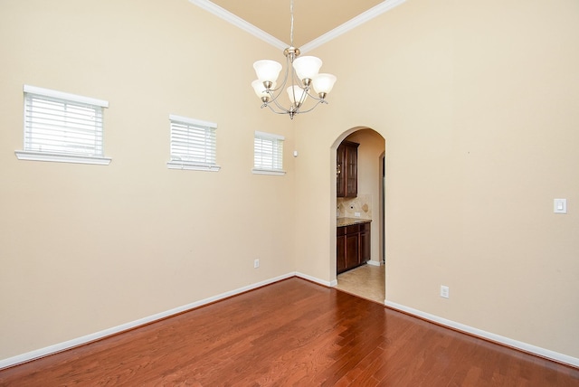 spare room featuring crown molding, plenty of natural light, light hardwood / wood-style floors, and a notable chandelier