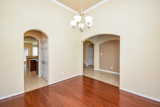 empty room with hardwood / wood-style floors, ornamental molding, and a chandelier