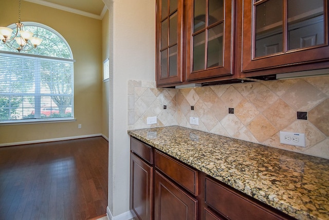 kitchen with pendant lighting, an inviting chandelier, crown molding, a wealth of natural light, and light stone counters