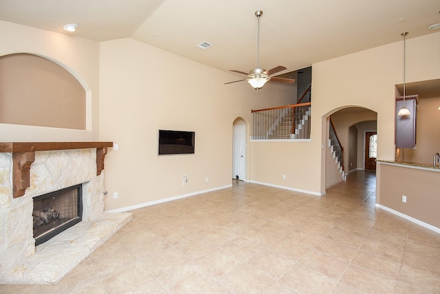 unfurnished living room with ceiling fan, a fireplace, light tile patterned floors, and lofted ceiling