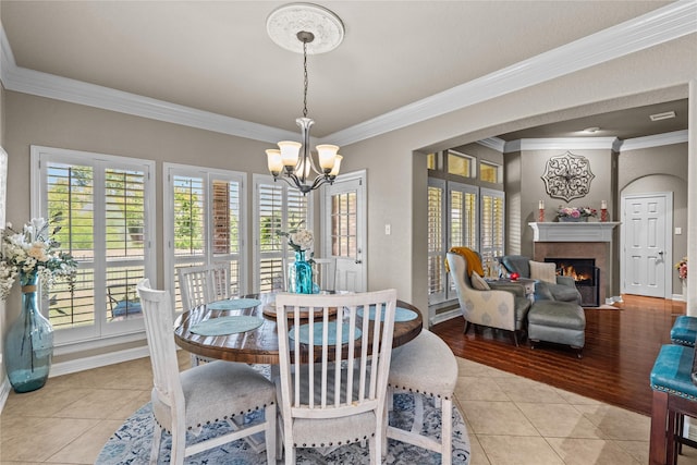 tiled dining space featuring a chandelier, a wealth of natural light, and ornamental molding