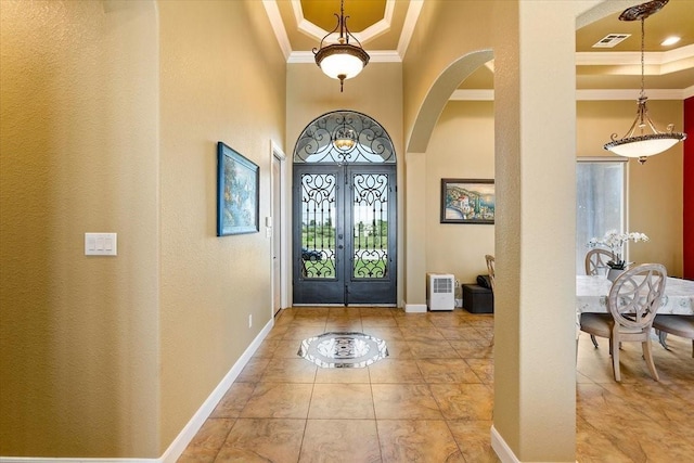 tiled foyer entrance with a raised ceiling, crown molding, and french doors