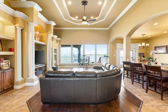 living room with a raised ceiling, ceiling fan with notable chandelier, built in features, and crown molding