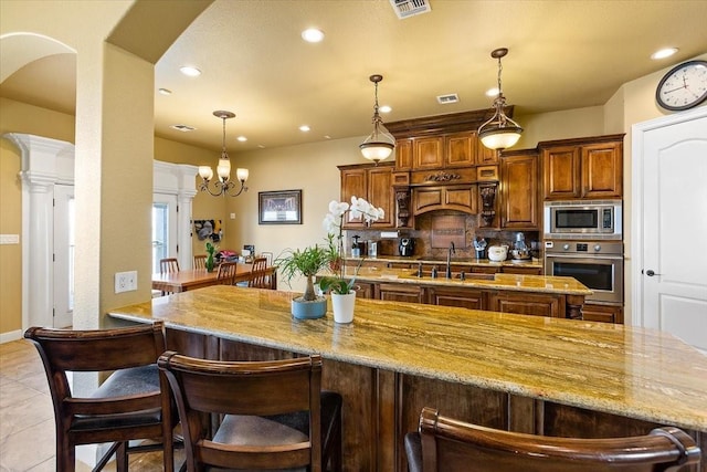 kitchen with sink, stainless steel appliances, an inviting chandelier, backsplash, and light tile patterned flooring