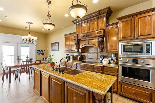 kitchen with stainless steel appliances, sink, decorative light fixtures, an inviting chandelier, and a center island with sink