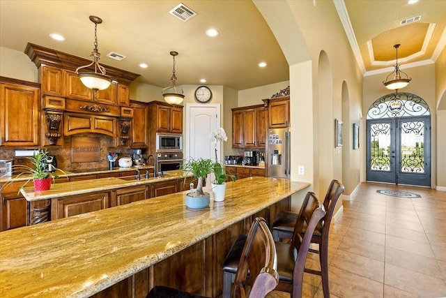 kitchen with pendant lighting, french doors, sink, a kitchen bar, and stainless steel appliances