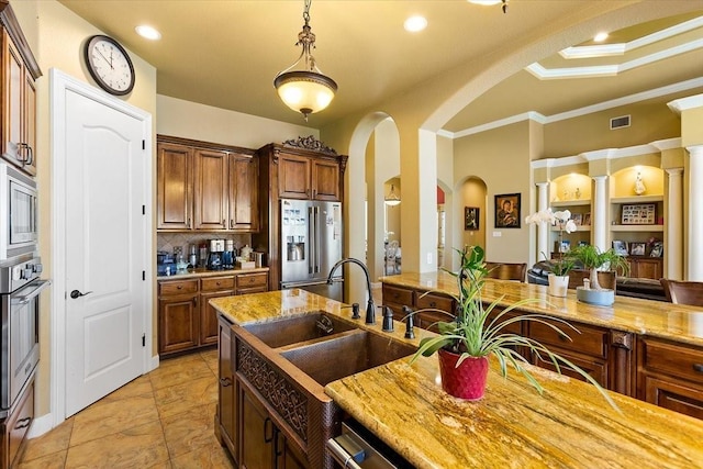 kitchen with hanging light fixtures, sink, crown molding, appliances with stainless steel finishes, and light stone counters