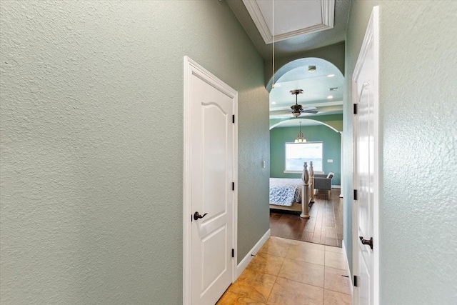 corridor featuring light tile patterned floors and ornamental molding