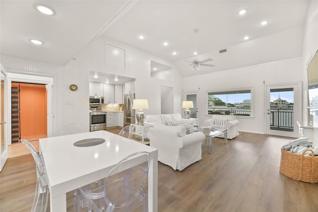 living room with ceiling fan, light wood-type flooring, and lofted ceiling