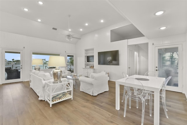 living room featuring built in shelves, light hardwood / wood-style floors, vaulted ceiling, and ceiling fan