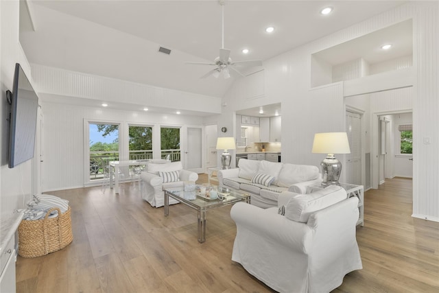 living room with ceiling fan, high vaulted ceiling, and light hardwood / wood-style floors