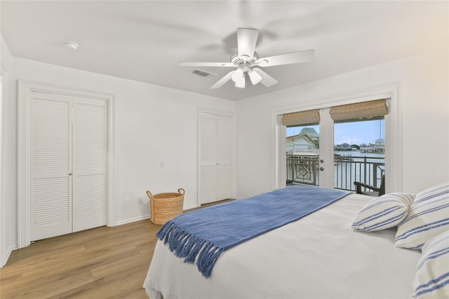 bedroom featuring access to outside, ceiling fan, a water view, light hardwood / wood-style flooring, and a closet