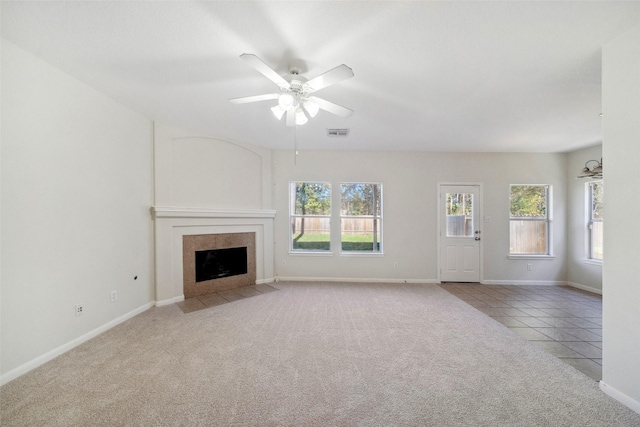 unfurnished living room with ceiling fan, light tile patterned floors, and a tile fireplace