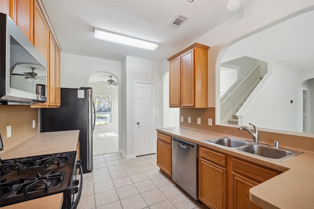 kitchen with appliances with stainless steel finishes, light tile patterned floors, ceiling fan, and sink