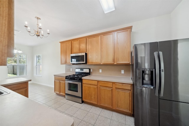 kitchen with appliances with stainless steel finishes, tasteful backsplash, light tile patterned floors, decorative light fixtures, and a chandelier