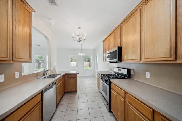 kitchen with stainless steel appliances, sink, light tile patterned floors, a notable chandelier, and hanging light fixtures