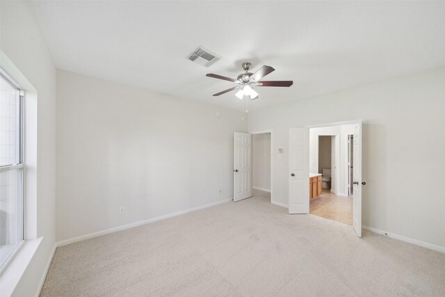 unfurnished bedroom featuring connected bathroom, ceiling fan, and light colored carpet