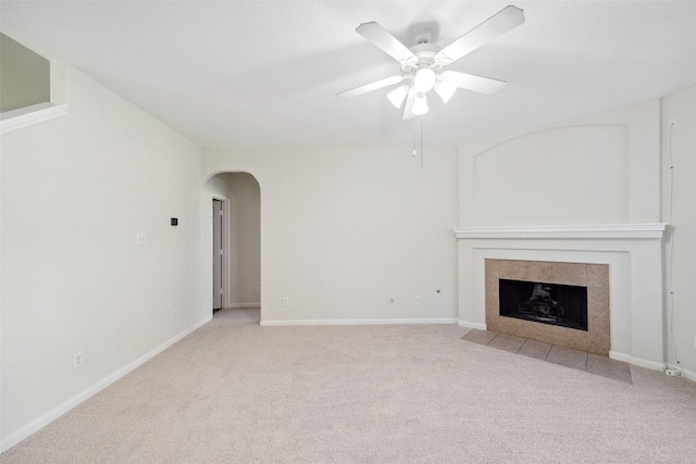 unfurnished living room with ceiling fan, light colored carpet, and a tile fireplace