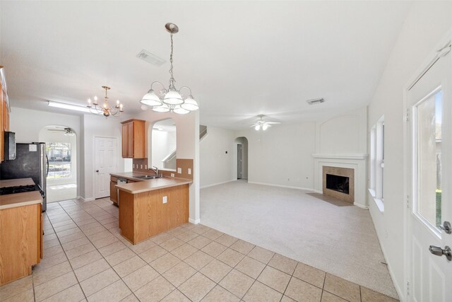 kitchen featuring kitchen peninsula, light carpet, ceiling fan with notable chandelier, sink, and decorative light fixtures