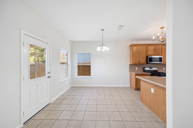 kitchen featuring black range with gas stovetop, light tile patterned floors, hanging light fixtures, and a notable chandelier