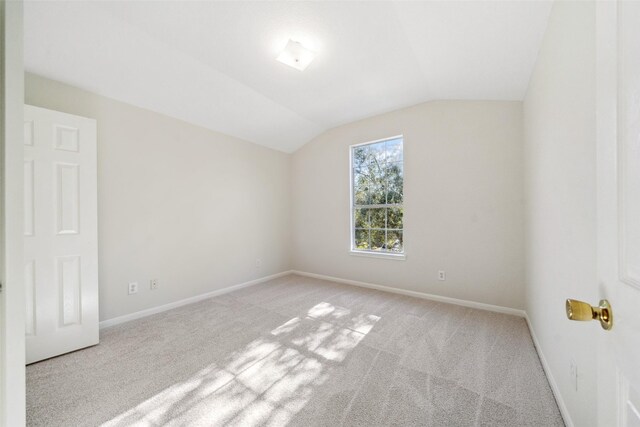 carpeted empty room featuring lofted ceiling