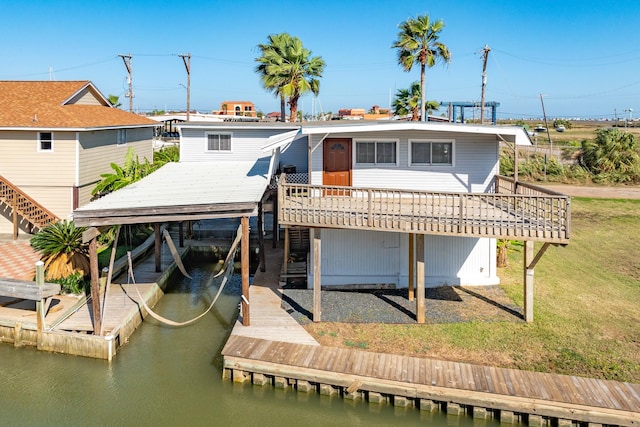 rear view of house with a deck with water view and a yard