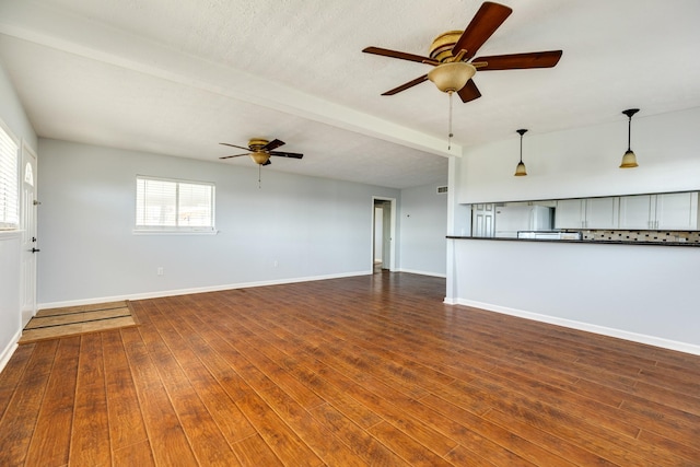 unfurnished living room featuring beam ceiling, a textured ceiling, dark hardwood / wood-style floors, and ceiling fan