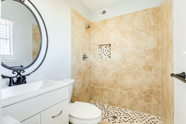 bathroom featuring vanity, toilet, and tiled shower