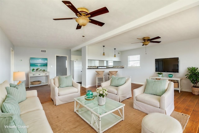 living room featuring ceiling fan, beam ceiling, and light wood-type flooring