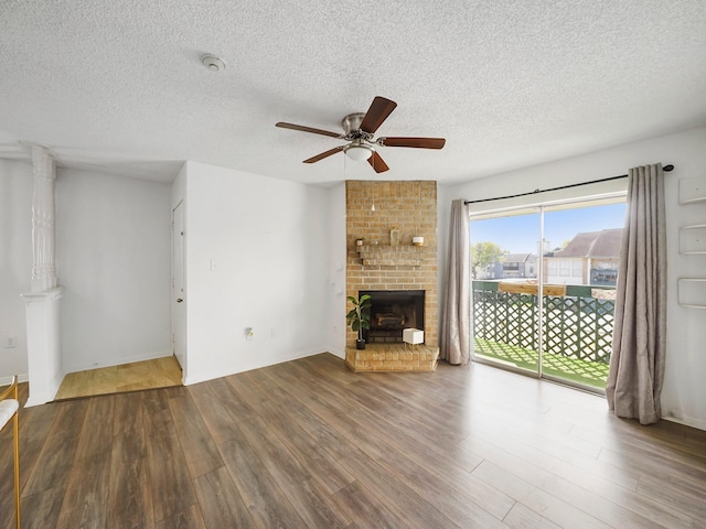 unfurnished living room with ceiling fan, hardwood / wood-style floors, a textured ceiling, and a brick fireplace