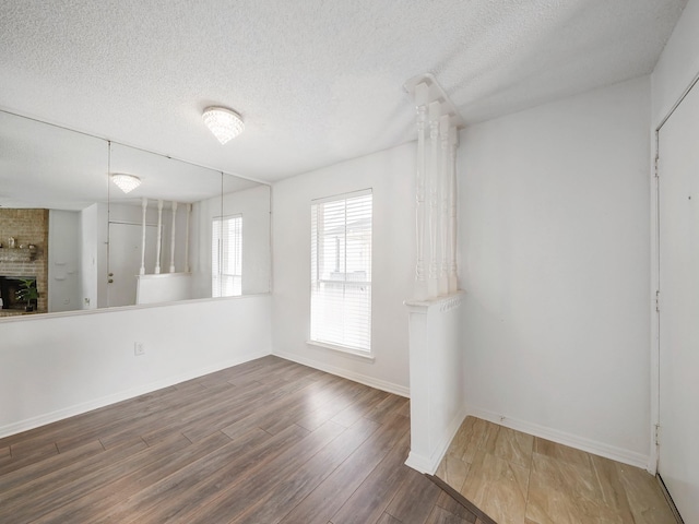 spare room featuring a large fireplace, wood-type flooring, and a textured ceiling