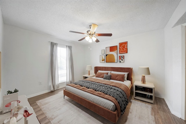 bedroom with ceiling fan, hardwood / wood-style floors, and a textured ceiling