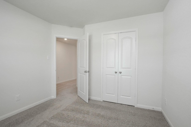 unfurnished bedroom featuring light carpet and a closet