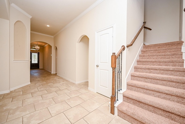 stairway featuring tile patterned floors, crown molding, and an inviting chandelier